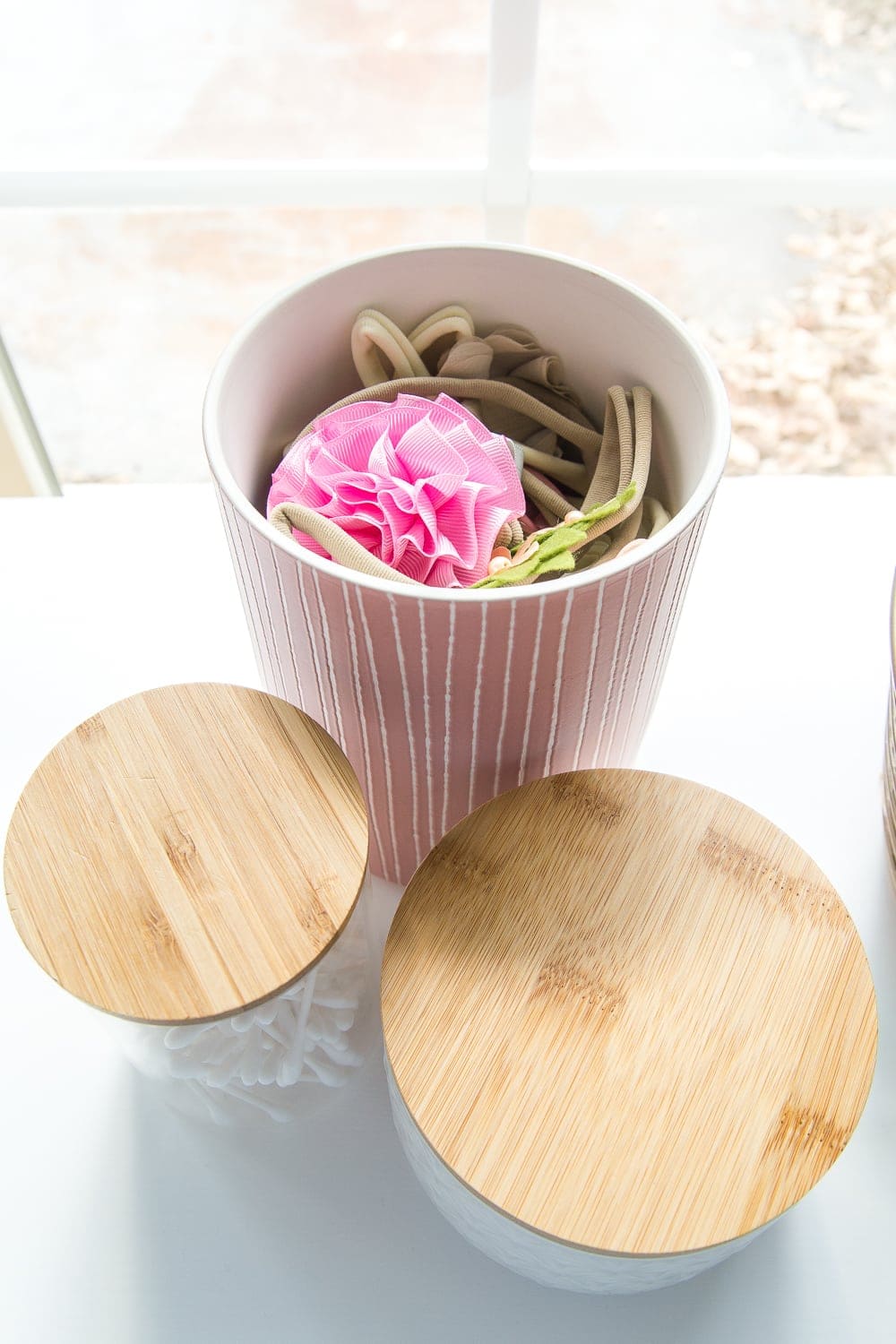 Nursery Organization | Use lidded canisters from the kitchenware aisle to store headbands and bows.