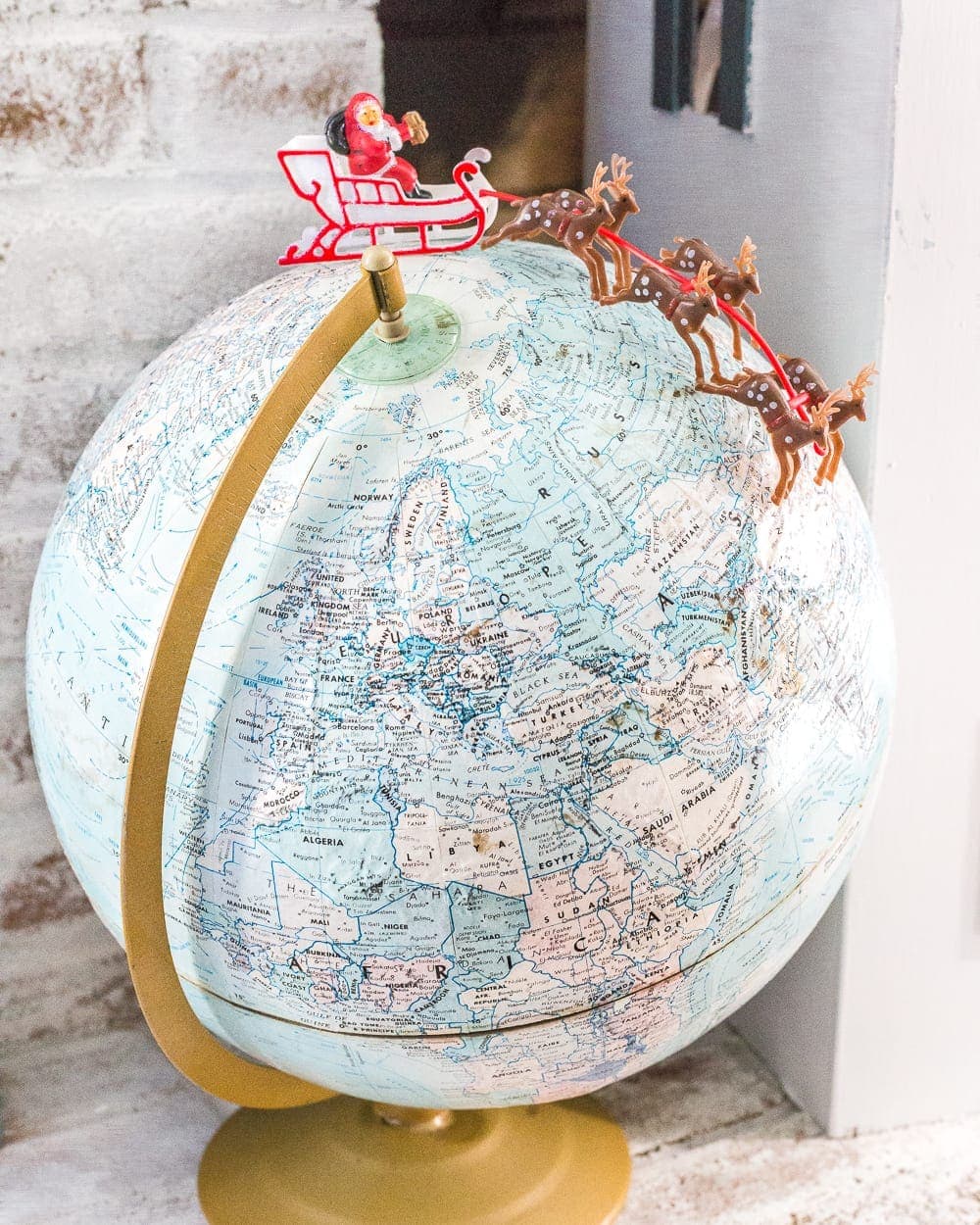 Vintage style Santa sleigh toy on top of a thrifted globe for whimsical Christmas decor