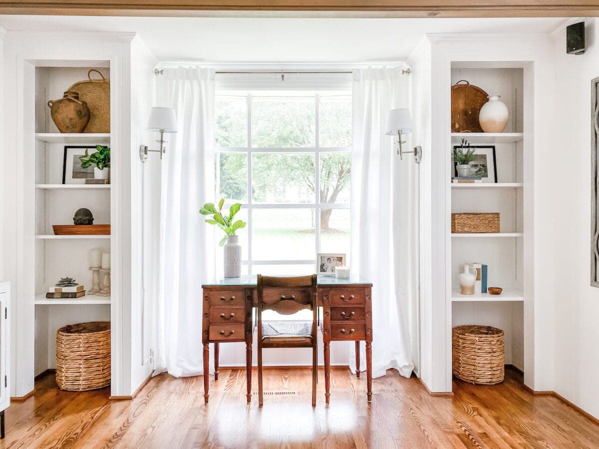 white office in living room with built-in shelves and desk in front of window