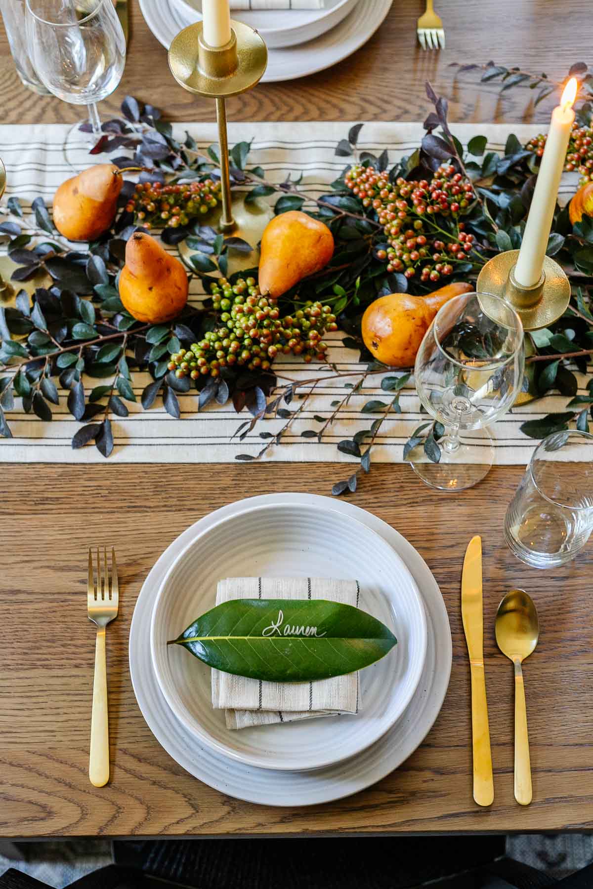 fall place setting with magnolia leaf place card and low centerpiece using leaves and pears