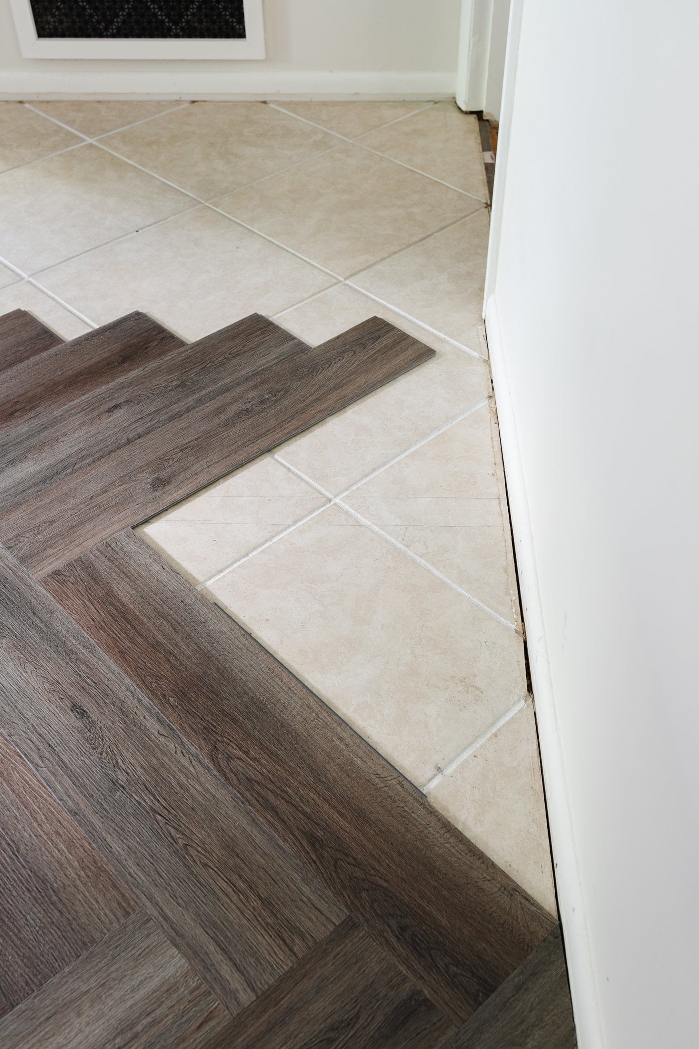 finishing a row of herringbone LVP flooring against a wall