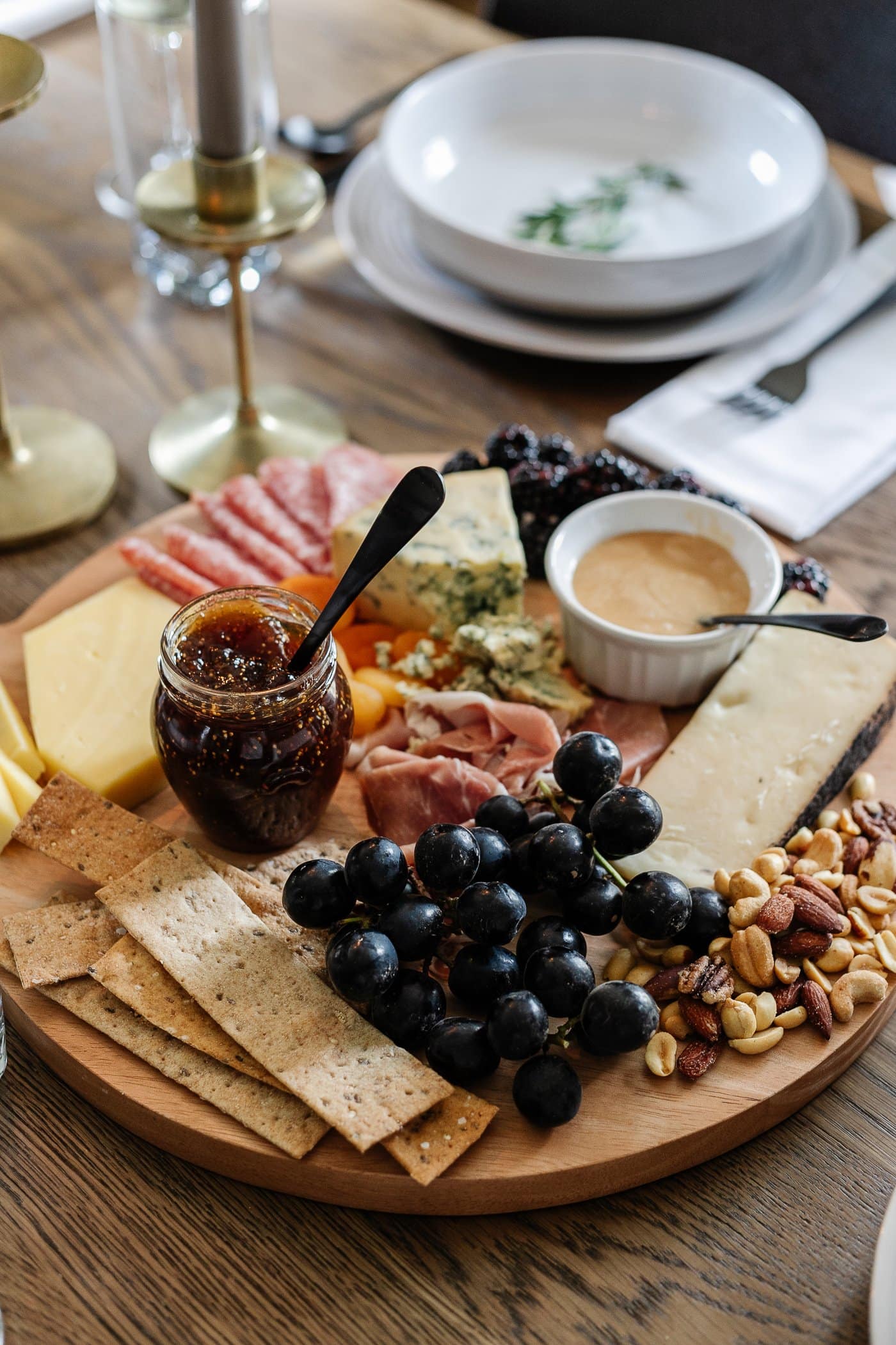 charcuterie board with meats, cheeses, crackers, jams, fruit, nuts, and honey