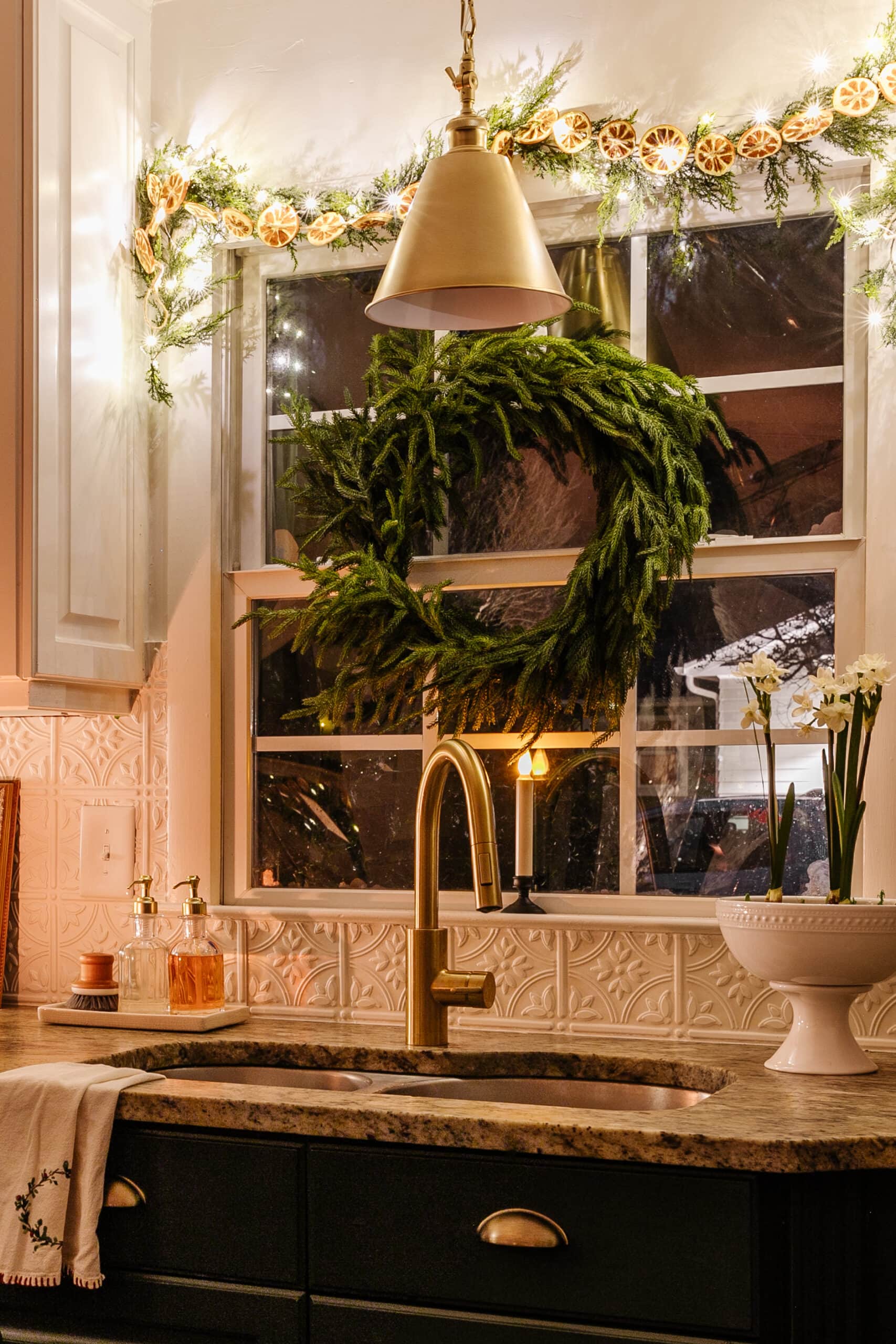 kitchen sink decorated for Christmas with wreath, garland, and bowl of paperwhites