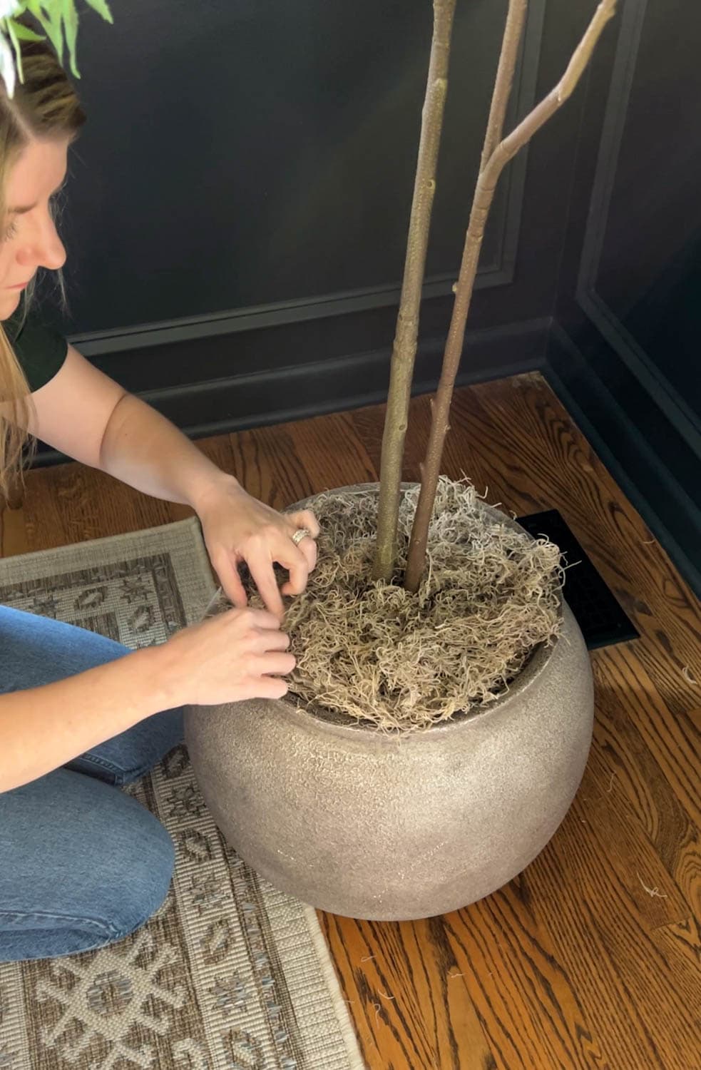 placing a fake tree in a large planter with moss to look real