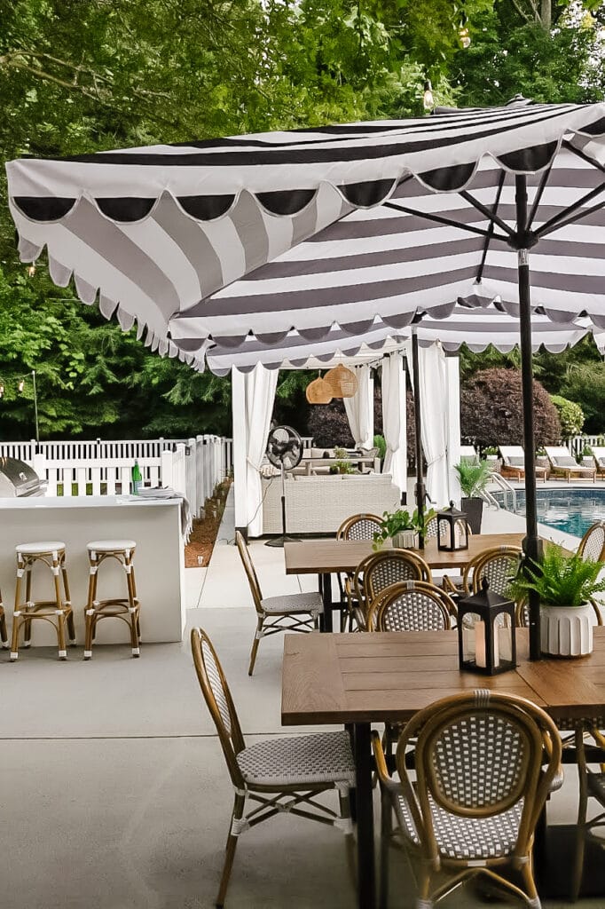 patio tables and chairs with umbrellas beside backyard kitchen and pool