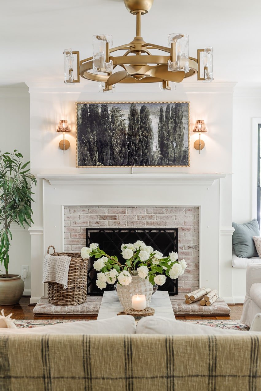 limewashed brick fireplace and gold fandelier in a living room
