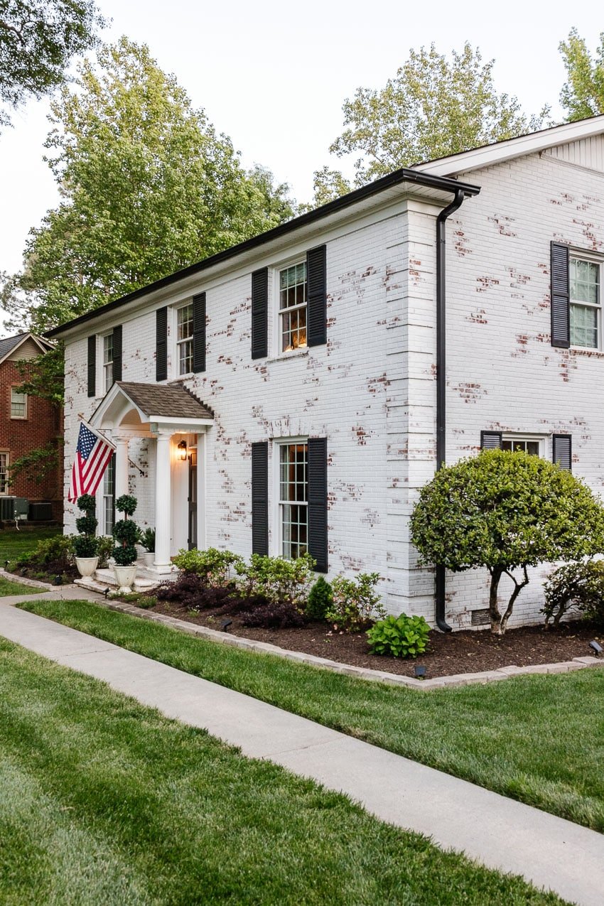 white limewashed brick house with flower bed makeover and green lawn facelift