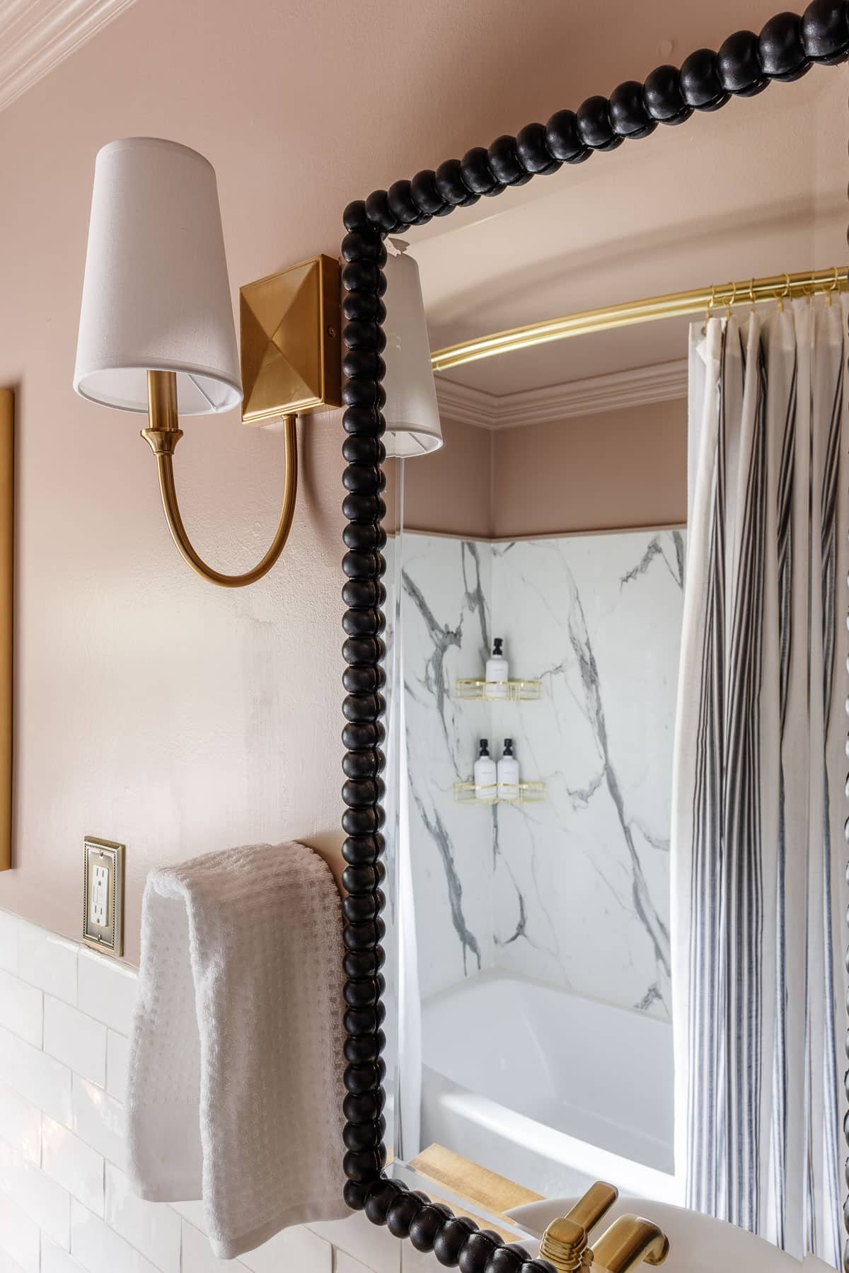 pink bathroom walls with black beaded mirrors and gold sconces