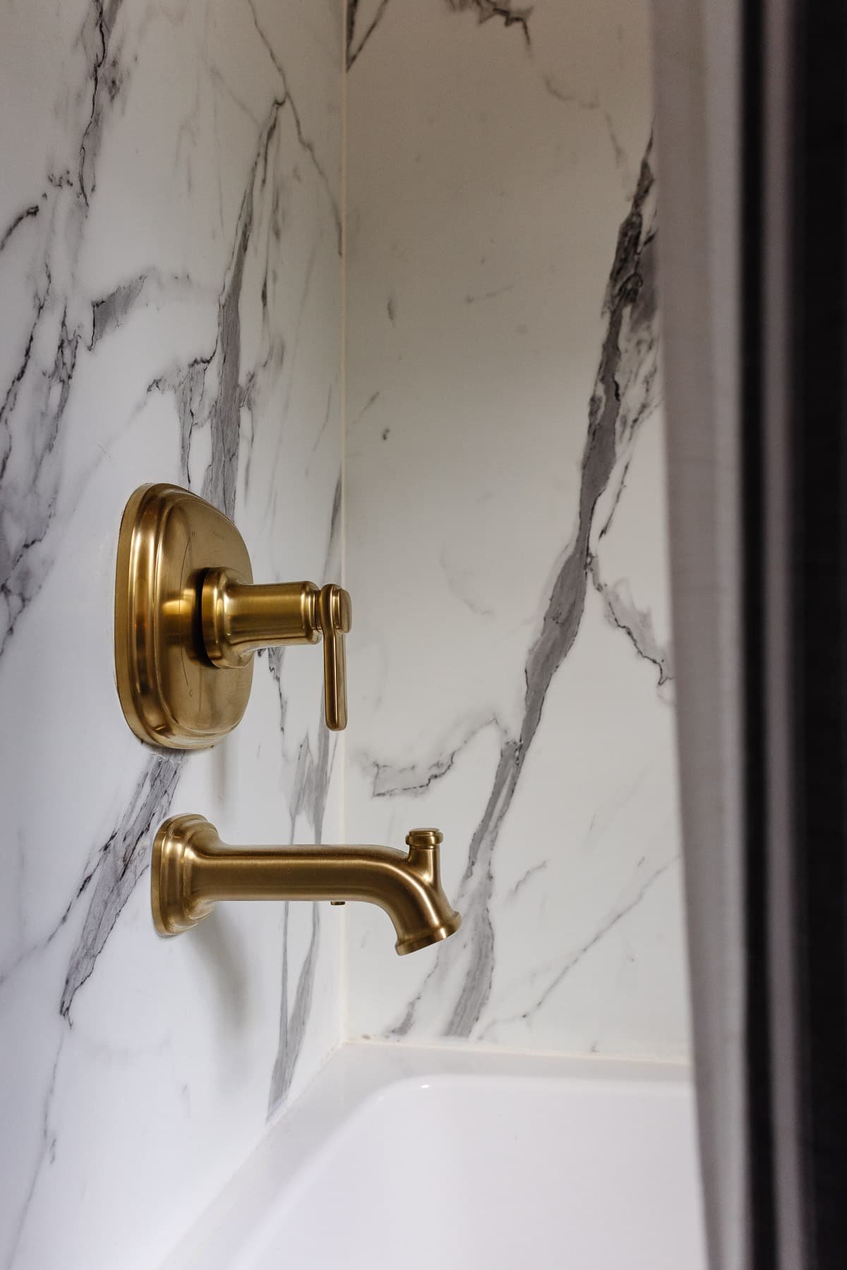 faux marble shower surround with gold tub faucet