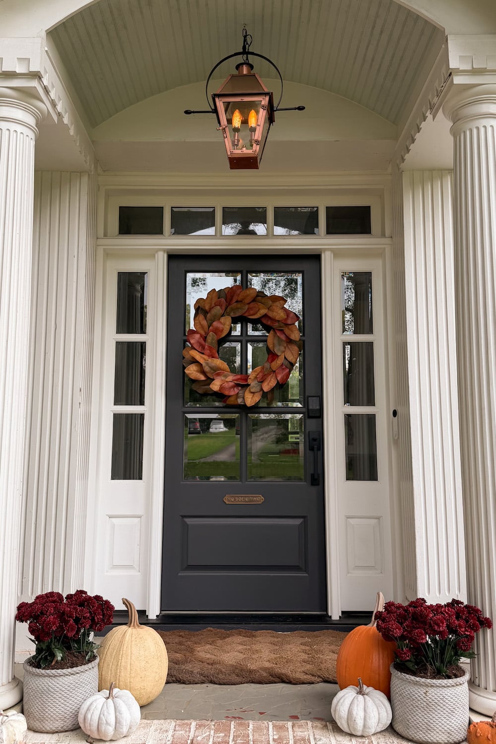fall front porch with faux pumpkins and fall leaf wreath