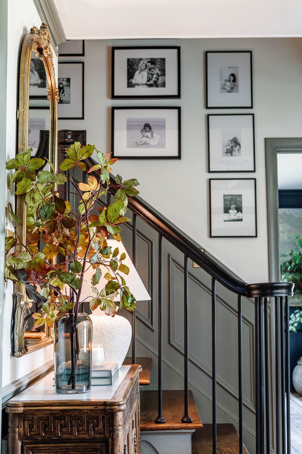 vase of tall fall stems on entryway table credenza and family gallery wall on staircase