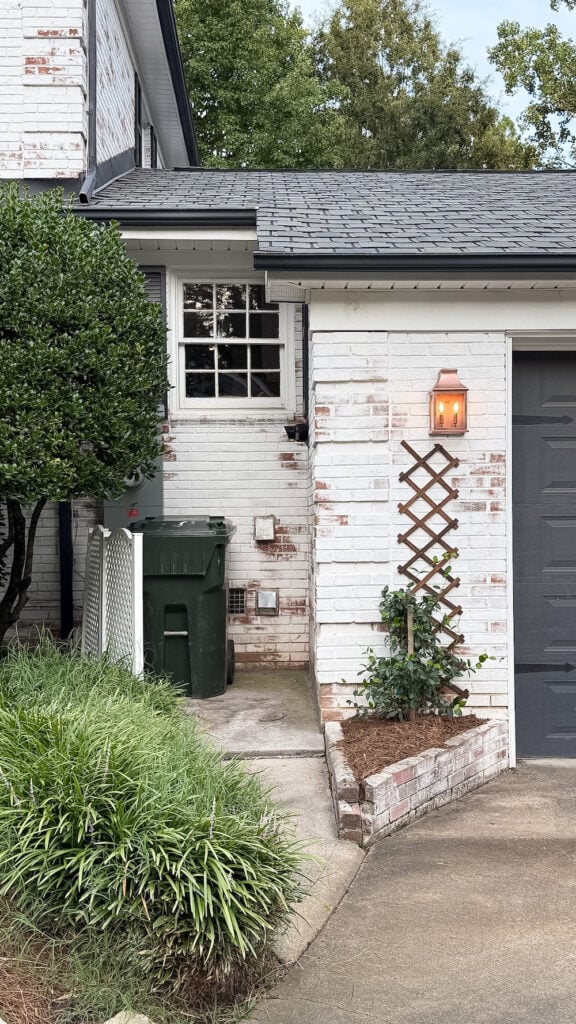 garage curb appeal with copper lanterns, star jasmine, and outdoor trash can hiding panels