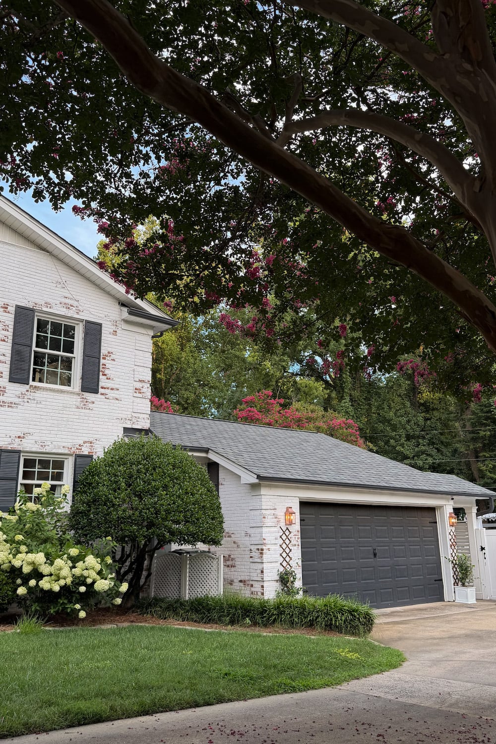garage curb appeal with copper lanterns, star jasmine, and outdoor trash can hiding panels