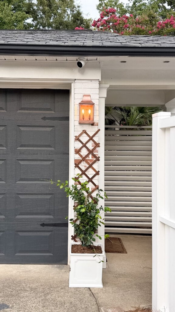 garage curb appeal with copper lanterns, star jasmine, and outdoor trash can hiding panels