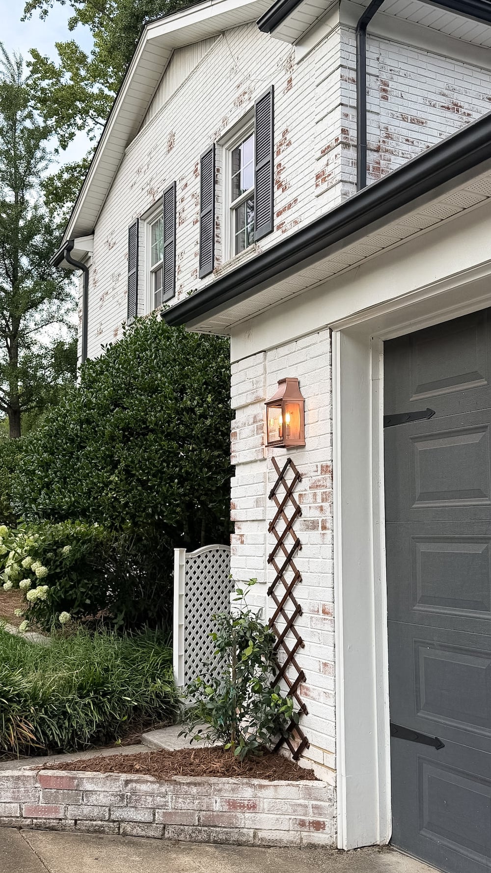 garage curb appeal with copper lanterns, star jasmine, and outdoor trash can hiding panels