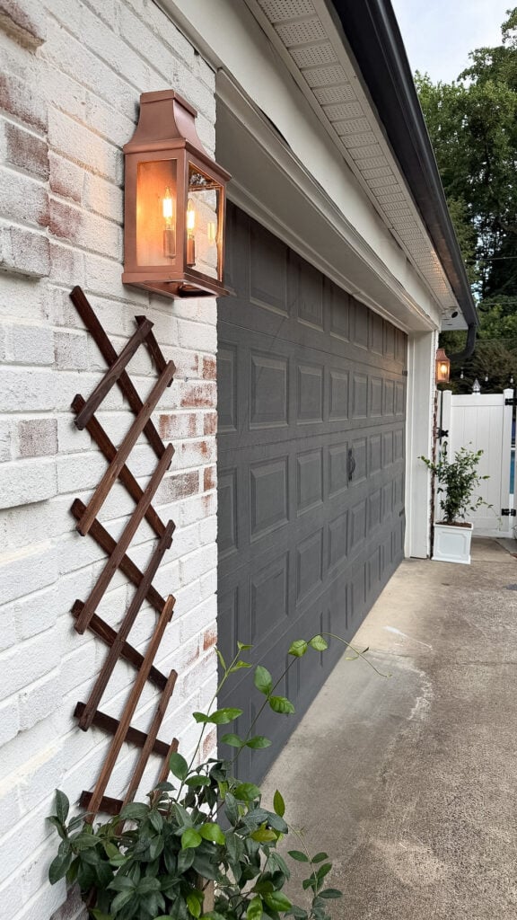 garage curb appeal with copper lanterns, star jasmine, and outdoor trash can hiding panels