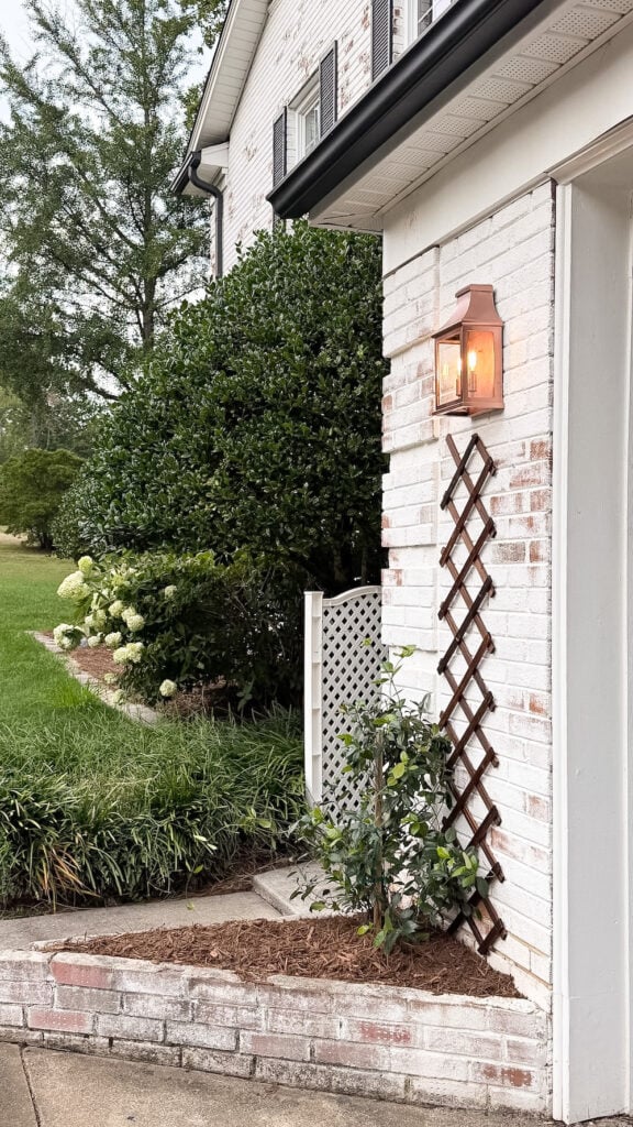 garage curb appeal with copper lanterns, star jasmine, and outdoor trash can hiding panels